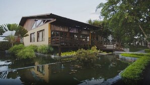 Ein modernes Gebäude mit einer Holzterrasse und einem Teich davor.