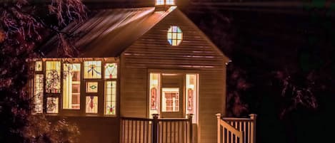 A small church with a cross on the roof, stained glass windows, and a wooden porch.