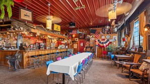 A restaurant with a long table, bar area, and various decorations including flags and a clock. - Romance Suite at B&B with full breakfast & mimosas! (Fredericksburg)