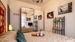 Een slaapkamer met een groot bed, een spiegel, een kroonluchter en kunstwerken aan de muren.