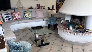 Ein modernes Wohnzimmer mit einer Eckcouch, einem Glastisch und einem Kamin.