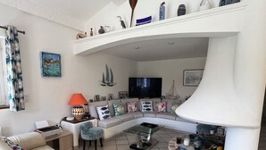 Ein modernes Wohnzimmer mit einer Eckcouch, einem Glastisch und einem Kamin.