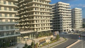A modern multi-story building with a curved facade, a visible entrance, and a clear sky. - Apartament Mamaia Nord (Năvodari)