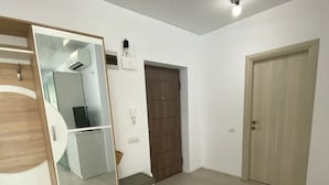 A spacious room with a large mirror, a wooden wardrobe, a bench, and a door. - Apartament Mamaia Nord (Năvodari)