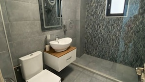 A modern bathroom with a toilet, sink, and shower. - Apartament Mamaia Nord (Năvodari)
