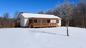 Una casa a un piano con portico e paesaggio innevato.