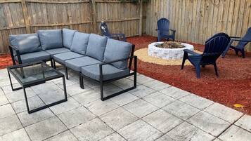 Een terras met een modulaire bank, twee stoelen en een kleine vuurkorf.