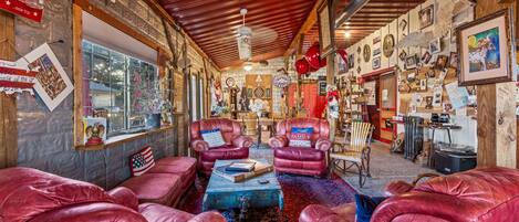 A cozy room with leather sofas, a coffee table, and a rustic wooden ceiling.