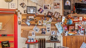 A room with a wooden wall adorned with various photographs and memorabilia, a wooden reception desk, and a red-framed bookshelf.