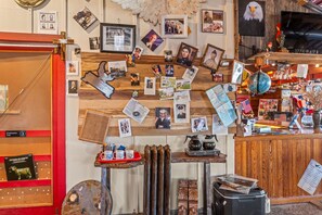 A room with a wooden wall adorned with various photographs and memorabilia, a wooden reception desk, and a red-framed bookshelf.