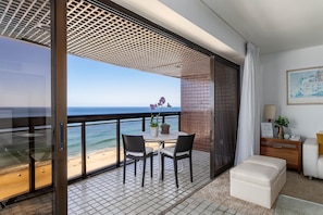 A balcony with a view of the beach and ocean, a table with chairs, and a small seating area with a sofa and a side table. - 801 (Rio de Janeiro)
