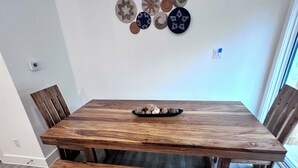 A wooden dining table with benches, a wall-mounted decorative plate collection, and a window with curtains. - 3 comfy king beds, hot tub, EV, cozy (Fort Worth)