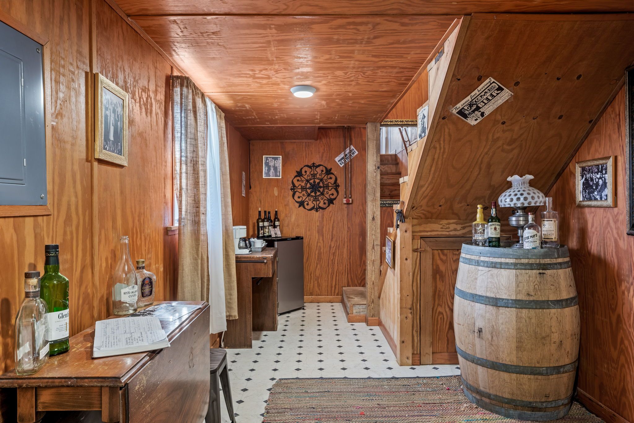 Un interior de madera con una cocina, un barril de madera y varias botellas.