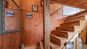 A wooden staircase with a handrail, wooden walls, and framed pictures.