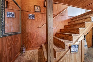Un escalier en bois avec une rampe, des murs en bois et des tableaux encadrés.