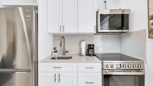 Una cocina compacta con refrigerador de acero inoxidable, microondas, estufa y pileta.