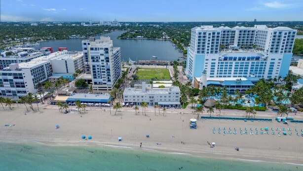 A coastal hotel with multiple buildings, a beach, and a marina.