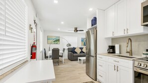 A modern kitchen with white cabinets, stainless steel appliances, and a dining area with a white table and chairs.
