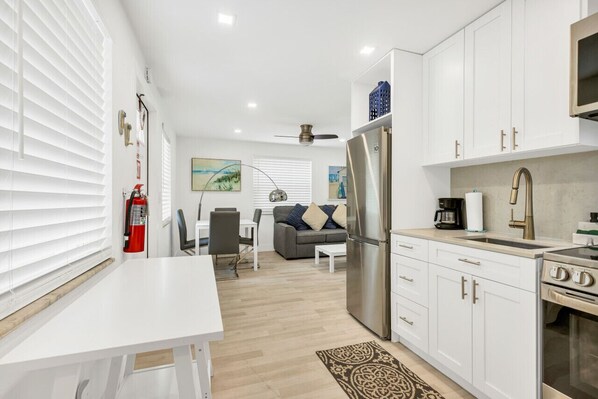 A modern kitchen with white cabinets, stainless steel appliances, and a dining area with a white table and chairs.