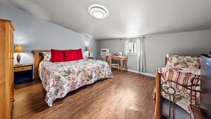 Ein Schlafzimmer mit Bett, Schreibtisch, Stuhl und Fenster.