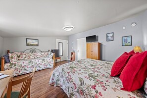 A room with two beds, a desk, a chair, a TV, and a cabinet.