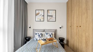 Ein modernes Schlafzimmer mit einem Bett, zwei Wandleuchten, einem Holzschrank und einem Nachttisch mit einem Frühstücksbrettchen.