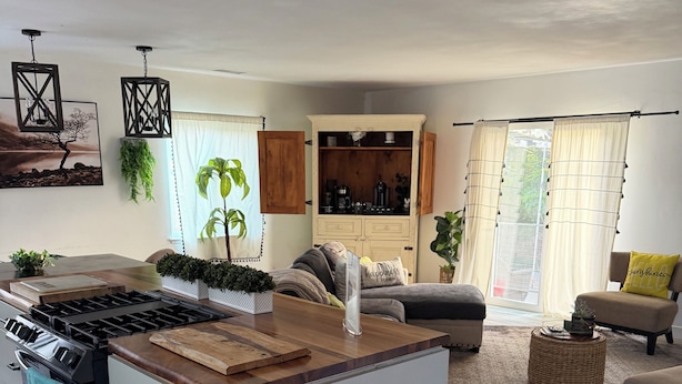 A modern kitchen with a central island, wooden flooring, and a dining area with a sofa and a coffee table. - Charming 3-bedroom house in fabulous Oxnard with WiFi (Oxnard)