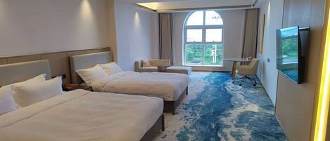 A hotel room with two beds, a TV, a small table, and a window with a view.