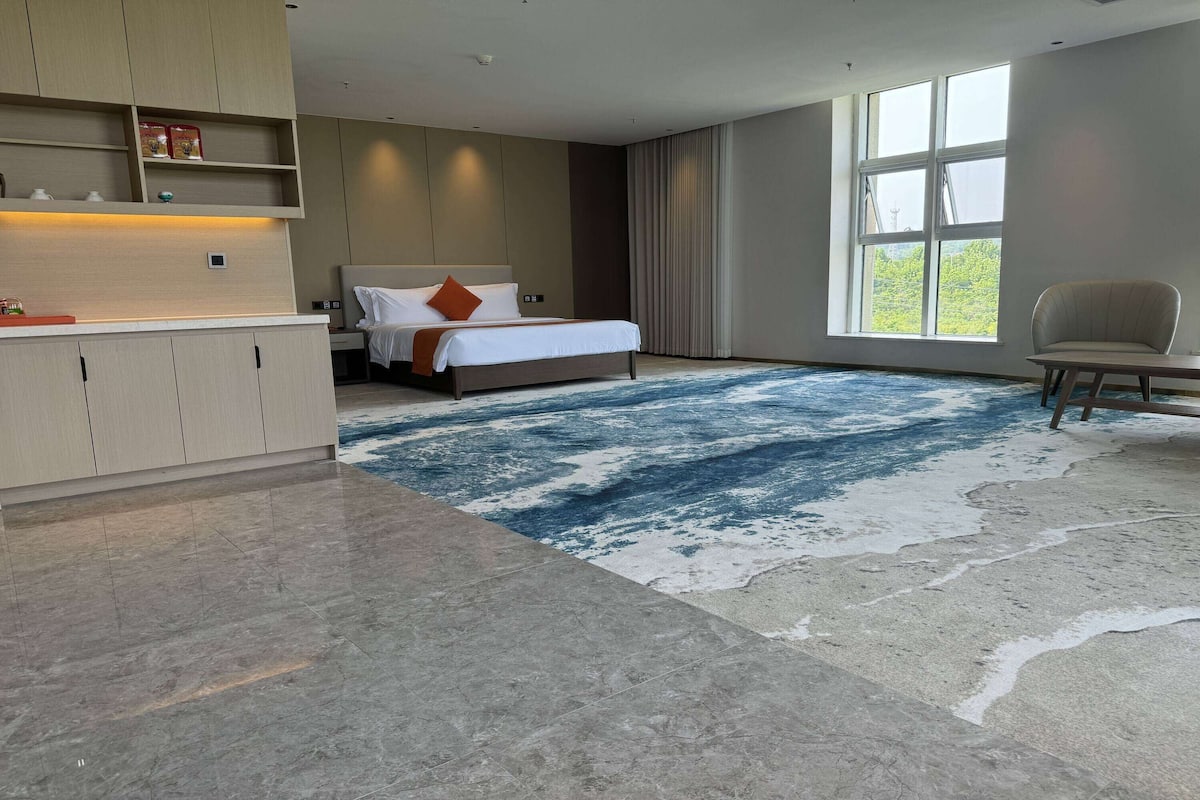 A modern hotel room with a large bed, a desk, and a view of the outdoors.