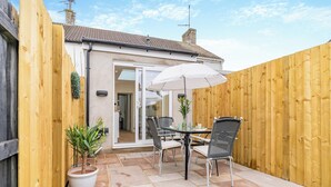 Eine Terrasse mit Tisch und Stühlen, einem Blumentopf und einem Holzzaun.