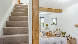 Eine Treppe führt zu einem Essbereich mit Tisch und Stühlen, einem Sofa und einem Spiegel an der Wand.