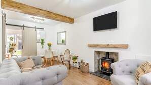 Ein modernes Wohnzimmer mit Kamin, einer Essecke mit Stühlen und einem Sofa.