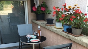 A patio with a table and chairs, a bottle, and potted plants.