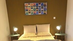 A bedroom with a bed, two bedside lamps, and a large abstract painting on the wall.