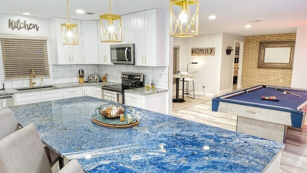 A modern kitchen with white cabinets, a blue marble island, and a pool table. - The Lily Pad- Pool Table Home (Tampa)