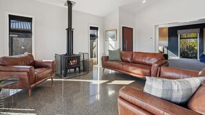 A spacious living room with a fireplace, leather sofas, and a large window.