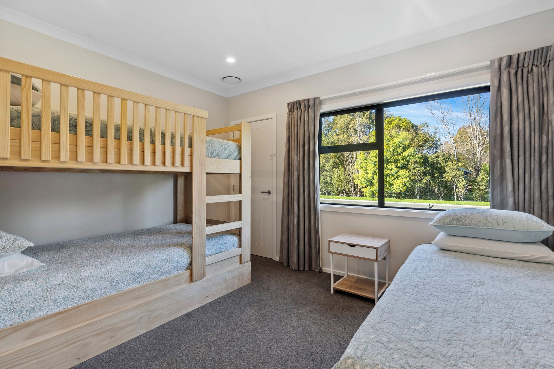 A bedroom with bunk beds, a small table, and a window with curtains.