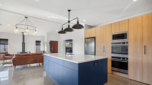 A modern kitchen with a central island, built-in ovens, and a dining area with a sofa.