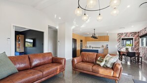 A modern living room with two leather sofas, a kitchen in the background, and a dining area.