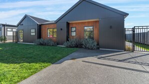 A modern two-story house with a grey exterior, a wooden front door, and a well-maintained lawn.