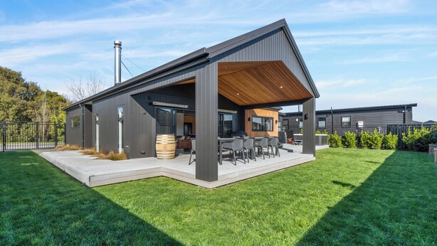 A modern house with a covered patio, a barbecue area, and a well-maintained lawn.