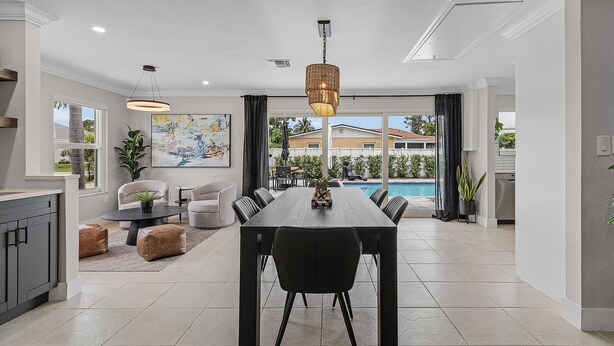 Une cuisine moderne avec un coin repas, de grandes fenêtres et une vue sur une piscine.