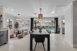 Une cuisine moderne avec un coin repas, de grandes fenêtres et une vue sur une piscine.