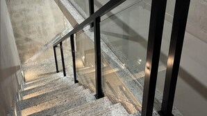 A staircase with a glass railing and a wooden door in the background. - Espaço de Festas e Descanso Cintia Lima (Petrovale Betim)