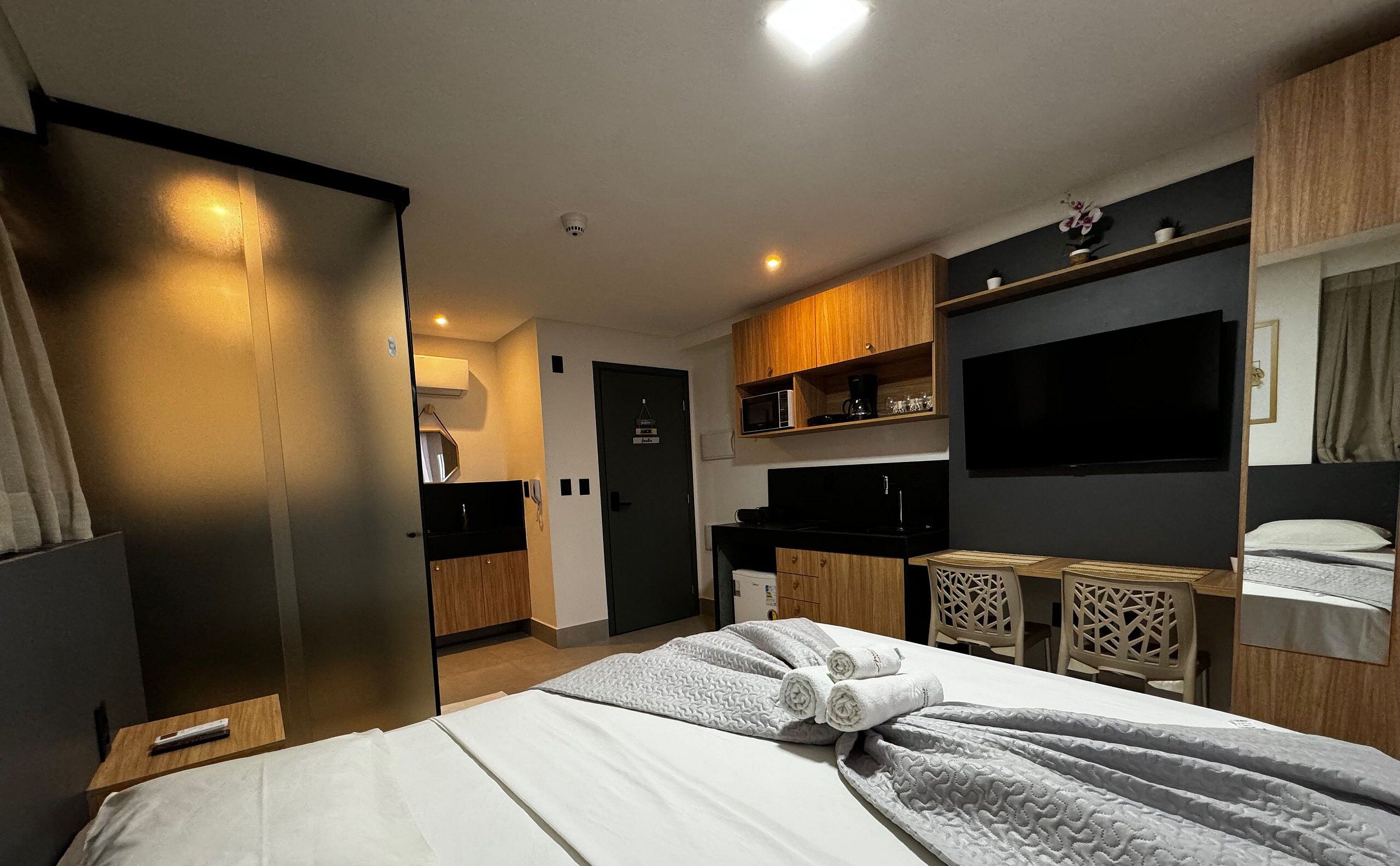 Une chambre d’hôtel moderne équipée d’un lit, d’un bureau, d’un four à micro-ondes et d’une télévision.