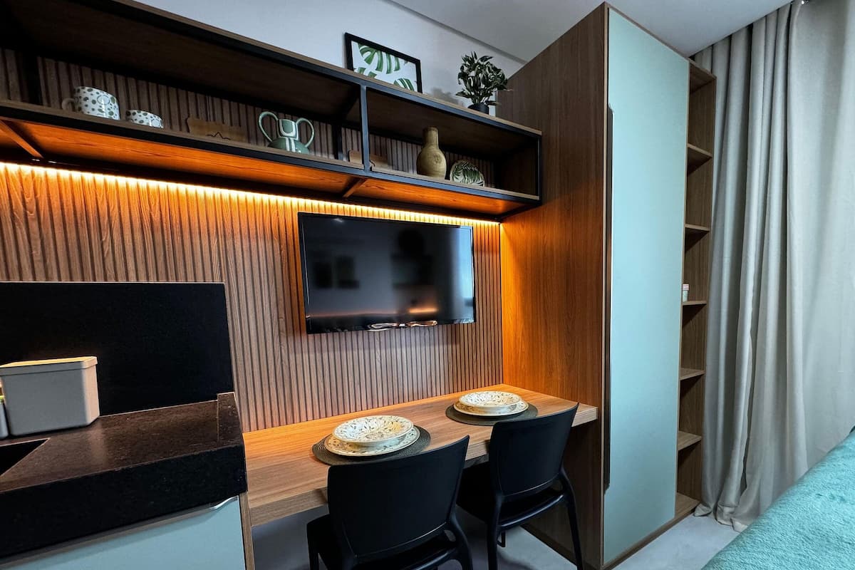 A modern dining area with a wooden wall, a flat-screen TV, and a dining table with chairs.