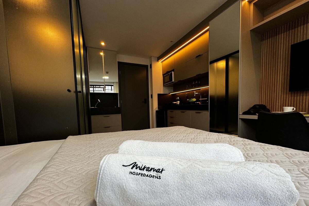 A hotel room with a bed, a minibar, a television, and a mirror.