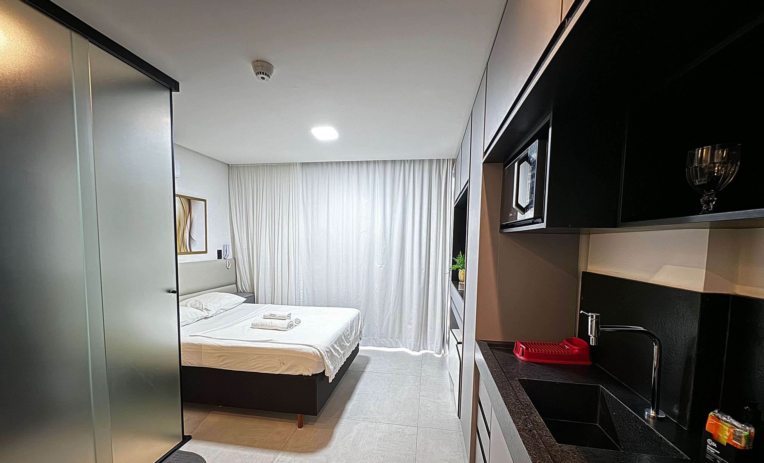 Une chambre d’hôtel moderne équipée d’un lit, d’une salle de bain et d’une kitchenette.