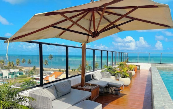 Un balcon avec vue sur l’océan, un plancher en bois et un espace salon extérieur.