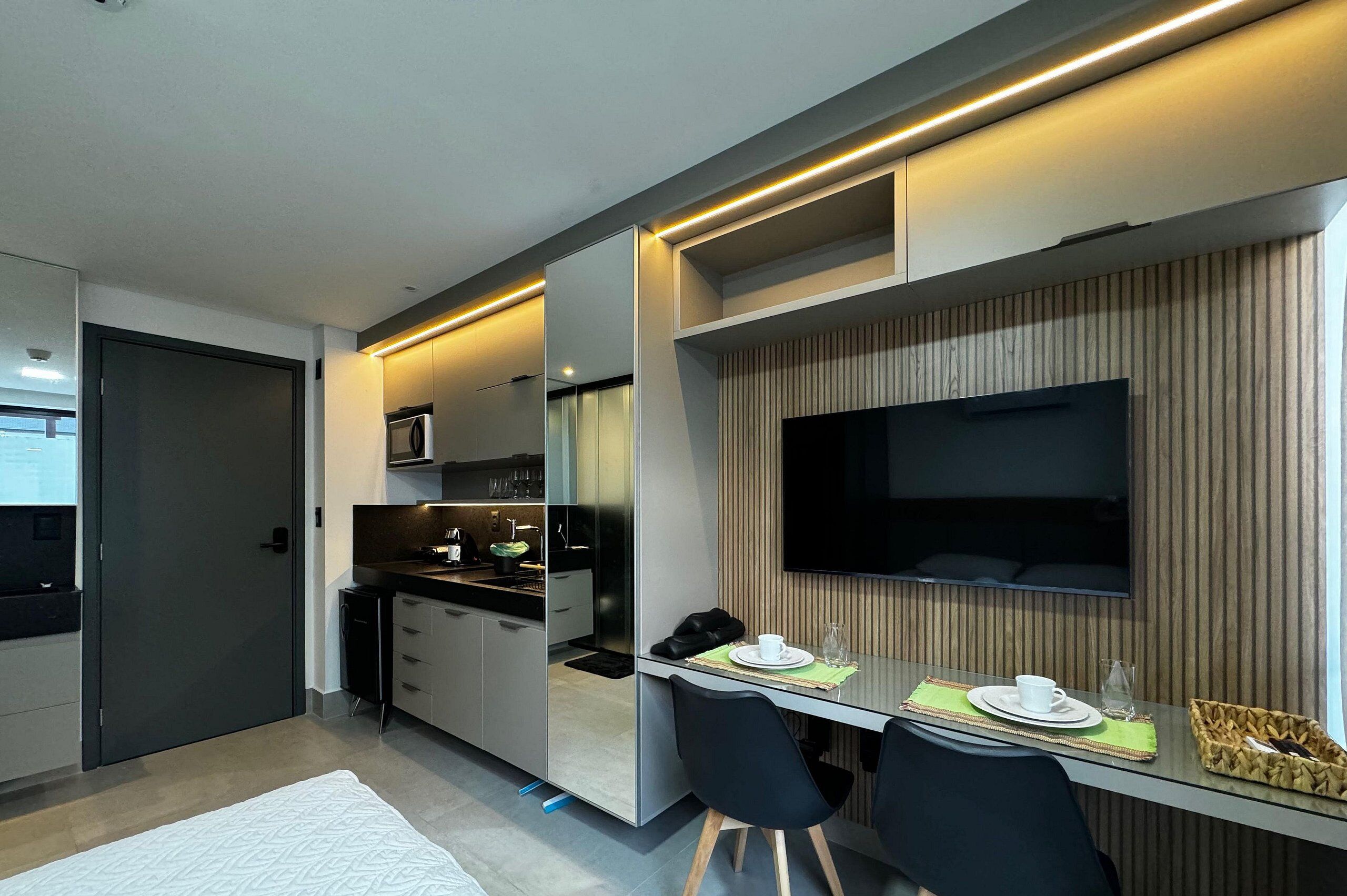 A modern kitchen with a dining area, a flat-screen TV, and a small table set for two.